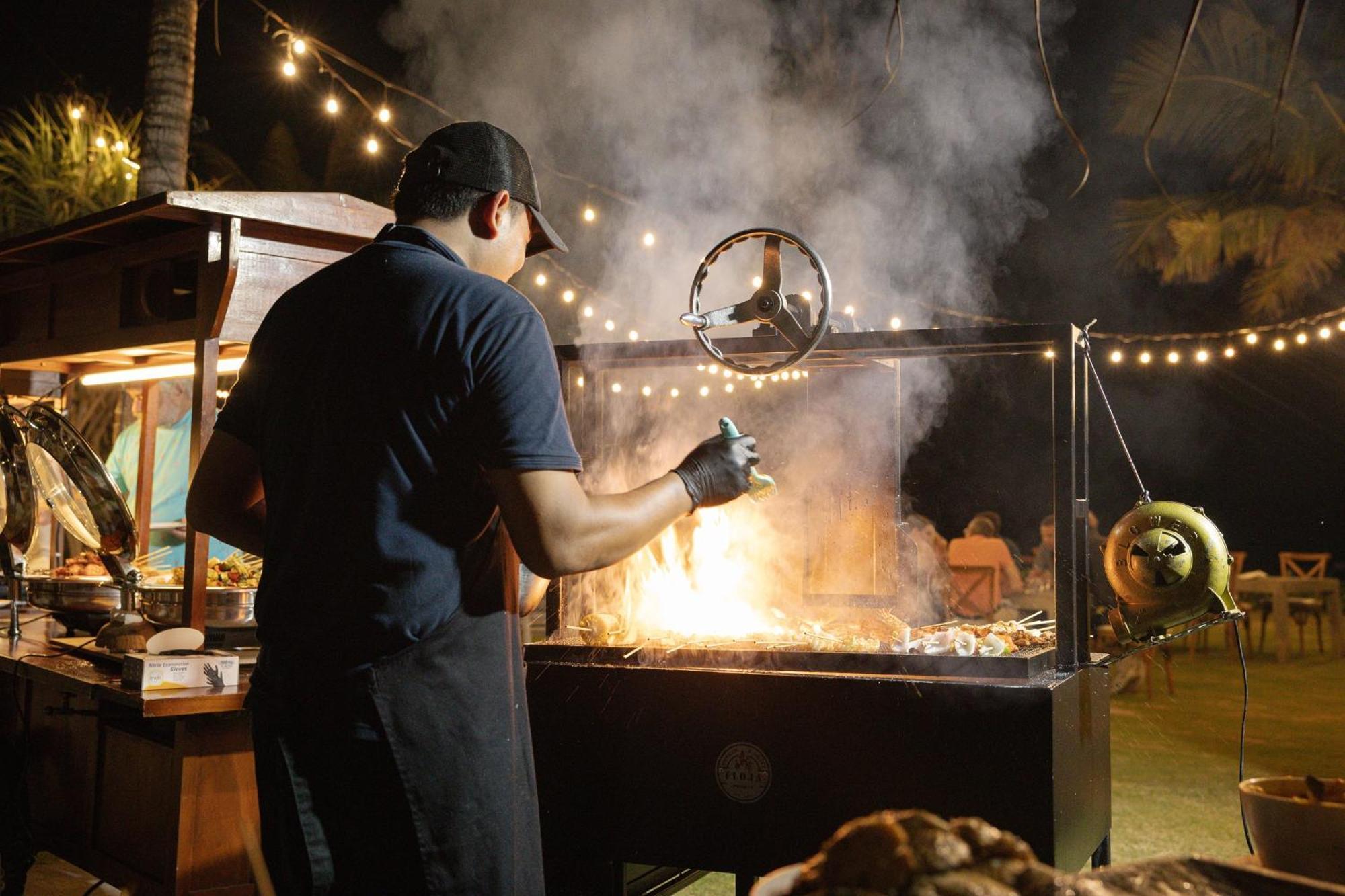 صدارة بوتيك بيتش ريزورت نوسا دوا المظهر الخارجي الصورة A chef cooking over a wood-burning grill
